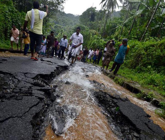 Poeple negotiate a damaged road stretch at Kandappanchal in Kodencheri, Kozhikode on Wednesday.