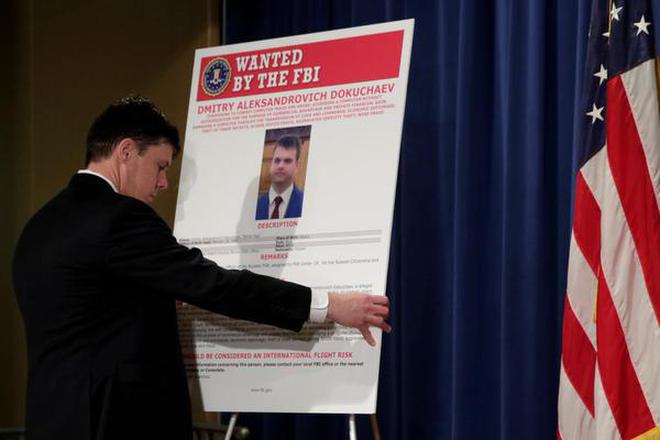 In this March 15, 2017 file photo, Department of Justice staffer installs a poster of a suspected Russian hacker before FBI National Security Division and the U.S. Attorney's Office for the Northern District of California joint news conference at the Justice Department in Washington, U.S.