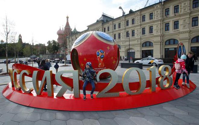 People gather near decorations for the upcoming 2018 FIFA World Cup with St Basils Cathedral seen in the background in central Moscow Russia June 7 2018