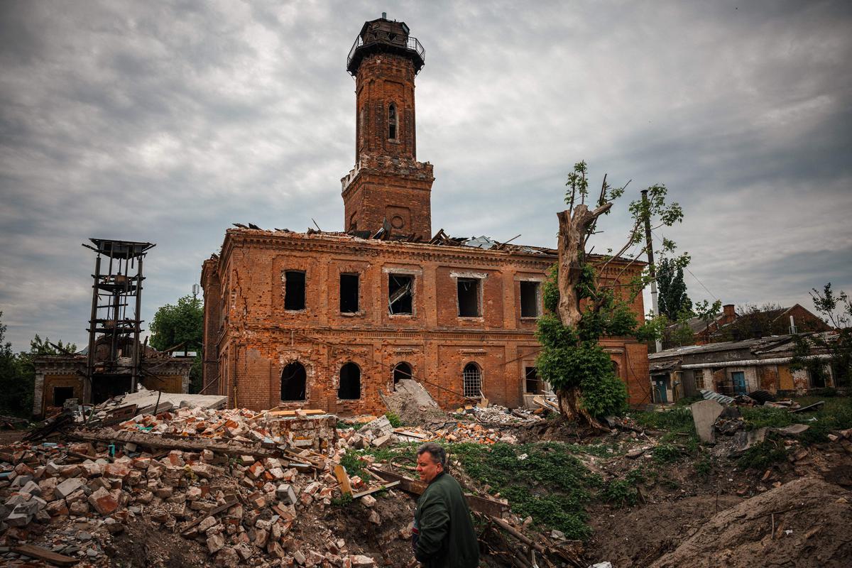 A local resident stands next the Karkhiv fire station, built in 1887, on May 26, 2022. - Shells and missiles have been falling on cities since the start of the war in Ukraine, damaging historic buildings. Cultural services try to preserve their memory and record the damages with advanced laser technology and 3D scans. 