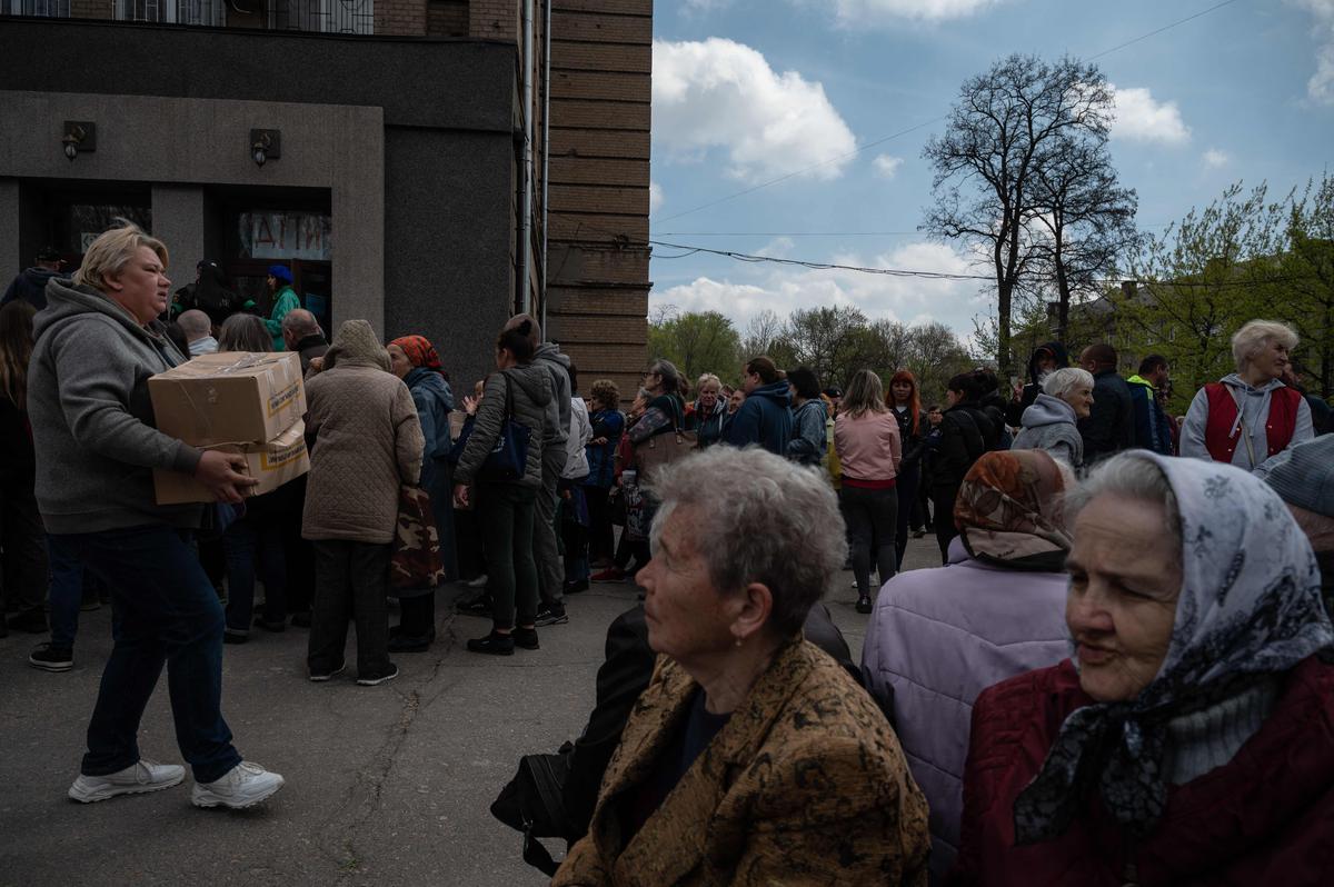Zaporizhzhia में आंतरिक रूप से विस्थापित लोगों और अन्य जरूरतमंद लोगों के लिए एक खाद्य वितरण केंद्र पर लोगों की कतार।