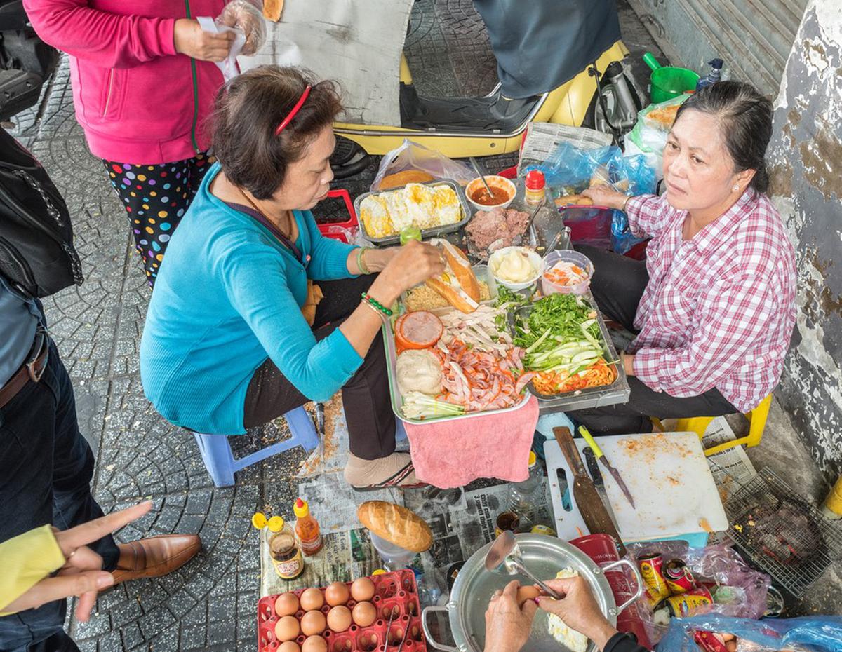 Women cook and sell banh mi sandwiches on the streets of Ho Chi Minh City.