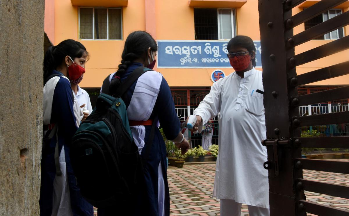 A teacher checks the temperature of a Class X student as she returns to school after a prolonged pandemic-induced closure in Bhubaneswar.