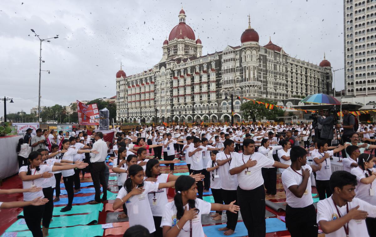 People perform yoga in front of the Taj hotel, during International Yoga Day in Mumbai, India, on June 21, 2022.
