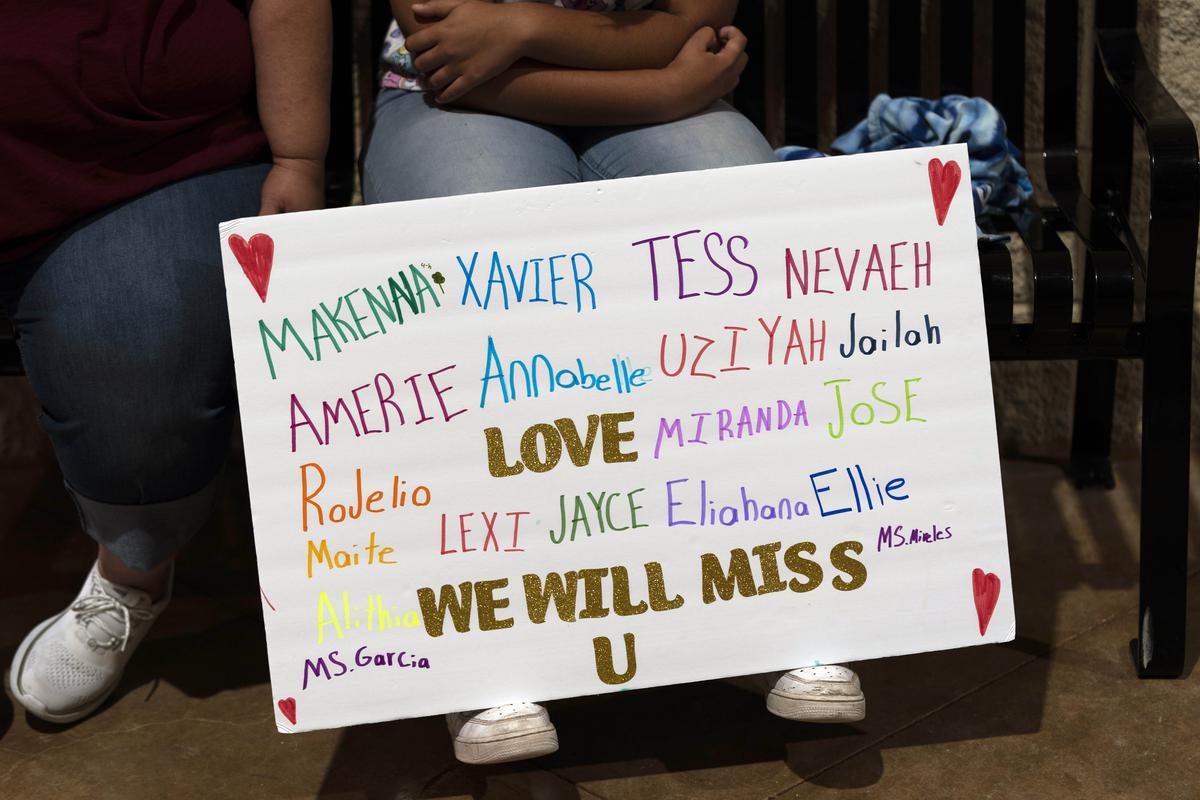 A student sits with a sign bearing the names of the Robb Elementary School shooting victims during a prayer vigil in Uvalde, Texas.