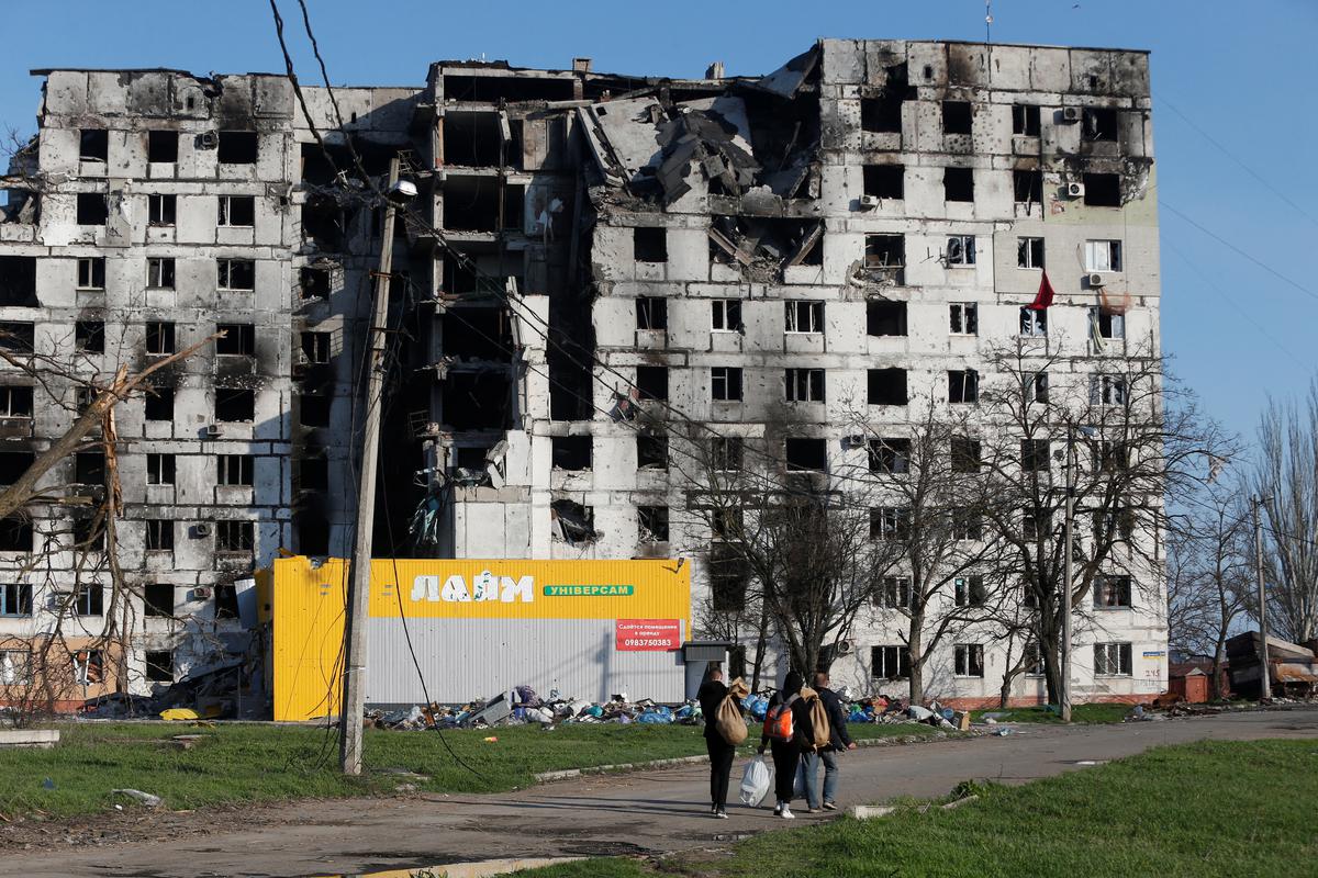 Local residents walk past an apartment building destroyed during Ukraine-Russia conflict in the southern port city of Mariupol, Ukraine on April 20, 2022.