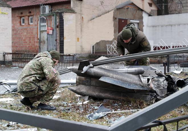 Police officers inspect the remains of a missile that fell in the street, after Russian President Vladimir Putin authorized a military operation in eastern Ukraine, in Kiev on February 24, 2022. 