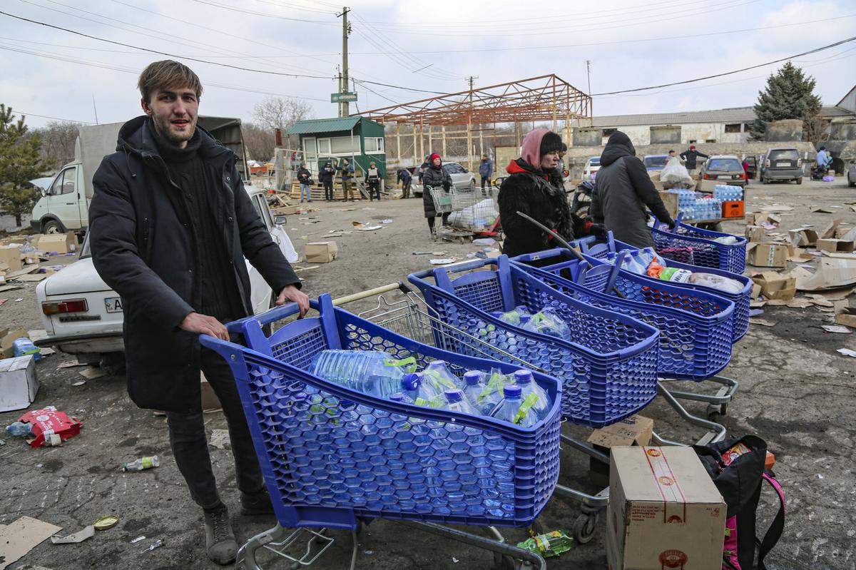 Local residents carry water from the food warehouse, on the territory which is under the Government of the Donetsk People’s Republic control, on the outskirts of Mariupol, Ukraine, on March 18, 2022. 
