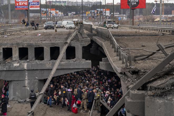  Ukrainians crowd under a destroyed bridge as they try to flee across the Irpin River in the outskirts of Kyiv, Ukraine, on March 5, 2022. 