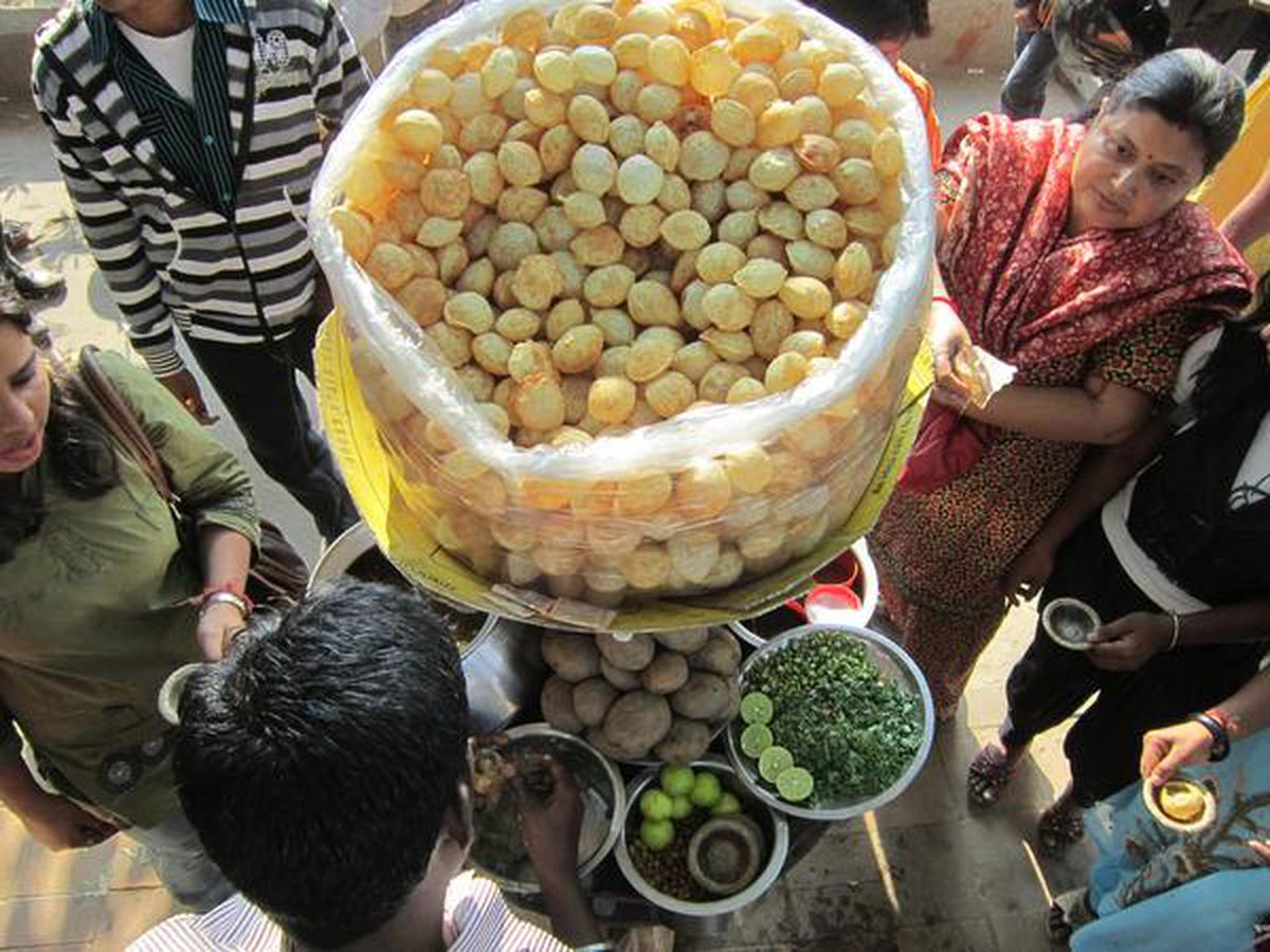 कोलकाता में एक सड़क के किनारे गोलगप्पे का आनंद लेते लोग।  गोलगप्पा एक प्रसिद्ध और लोकप्रिय भारतीय स्ट्रीट फूड है।