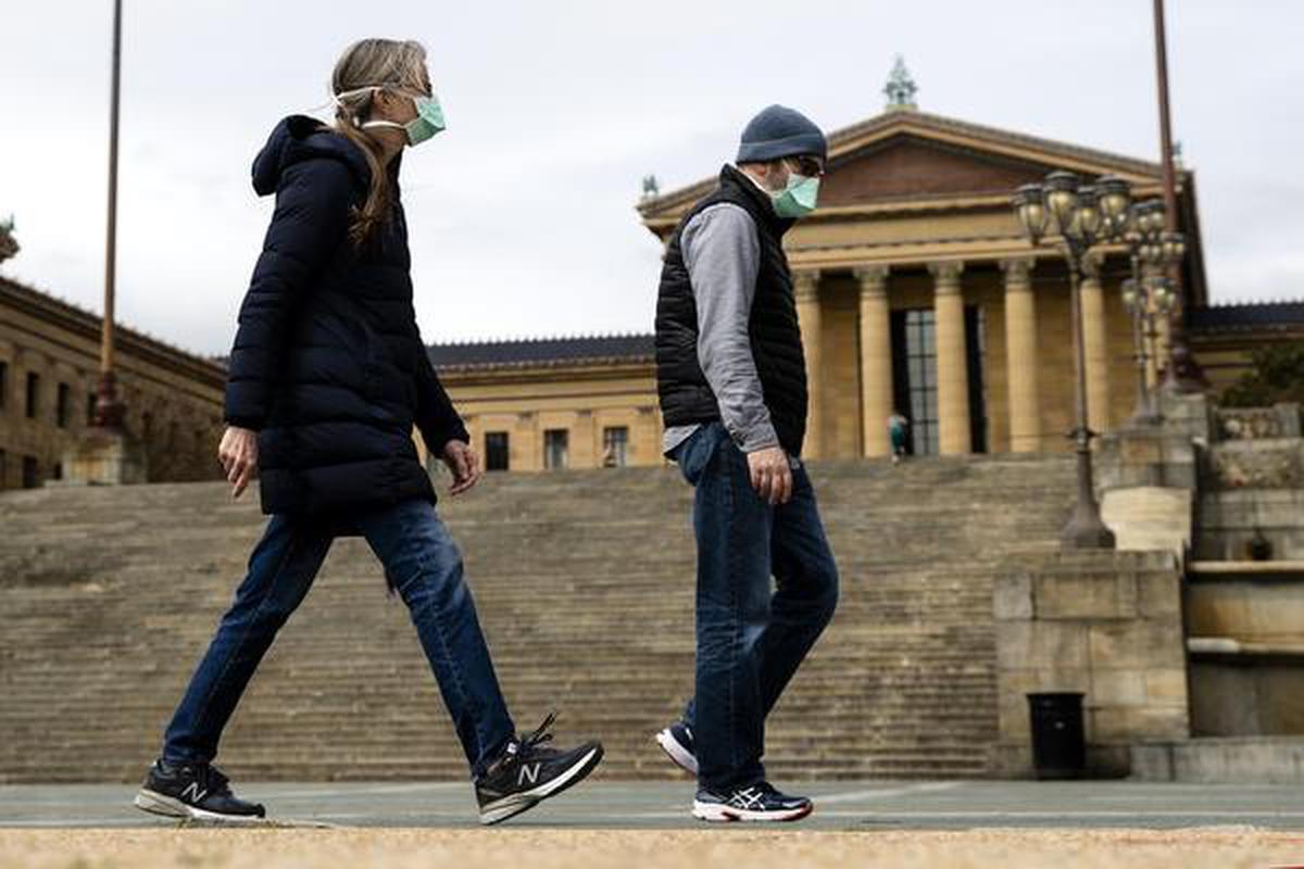 A couple in protective masks during the Coronavirus outbreak walk past the Philadelphia Museum of Art