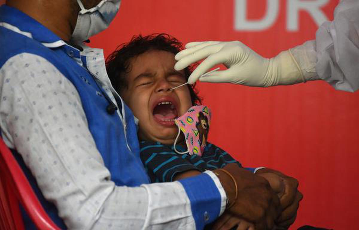 A child reacts while a doctor takes a nasal swab to test for SARS-CoV-2 at a primary healthcare centre in Kochi.