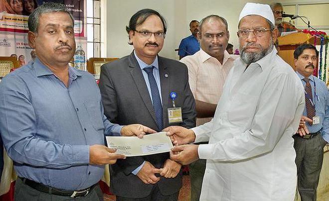 Collector K. Rajamani distributing loan to an entrepreneur at a support and outreach programme for MSME in Tiruchi on Tuesday.