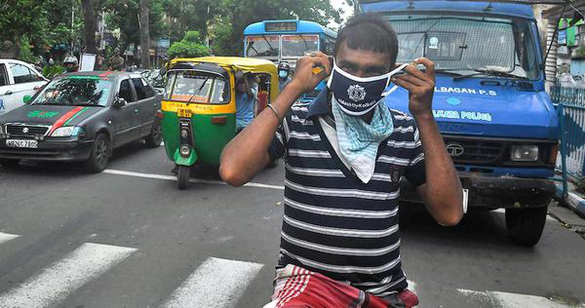 A police officer (not in picture) gives a mask to a cyclist as part of an awareness campaign to control the spread of COVID-19 in Kolkata on Monday.