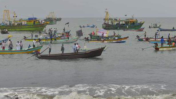 Fishermen ride boats with black flags in protest