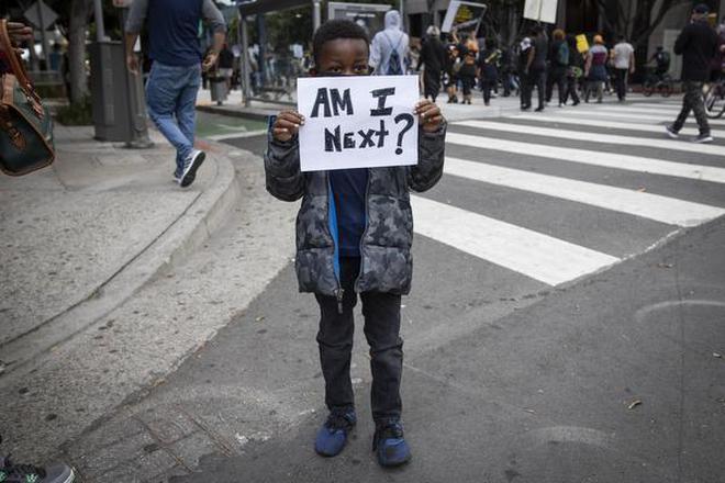A boy holds a sign during a protest in downtown Los Angeles, Friday, May 29, 2020, over the death of George Floyd.