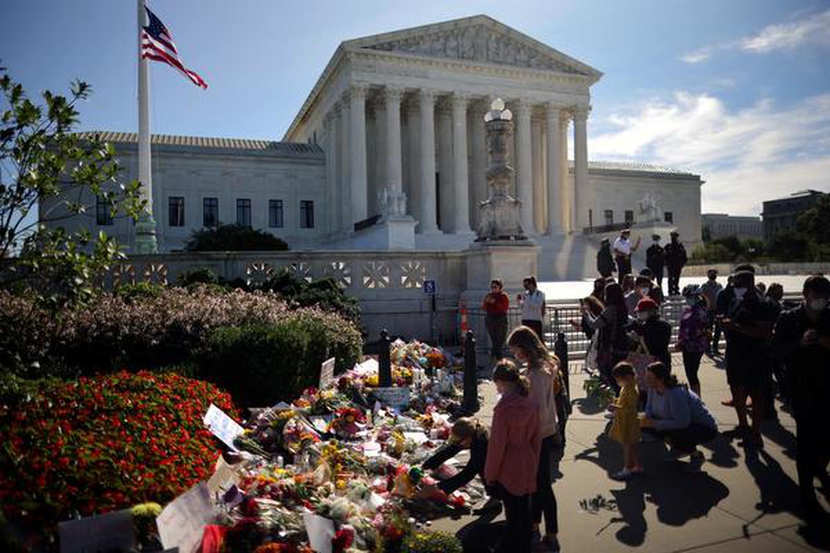 A woman puts flower on a memorial altar as people gather in front of the U.S. Supreme Court following the death of U.S. Supreme Court Justice Ruth Bader Ginsburg, in Washington, U.S. on September 19, 2020.