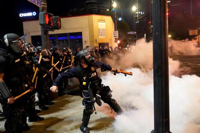 A police officer throws a canister of gas during a protest against the deaths of Breonna Taylor by Louisville police and George Floyd by Minneapolis police, in Louisville, Kentucky, U.S. May 29, 2020.