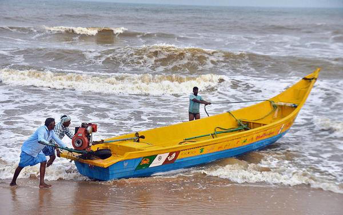 Fishermen move a boat to safety in the coastal village of Kothapatnam in Prakasam district on Wednesday.