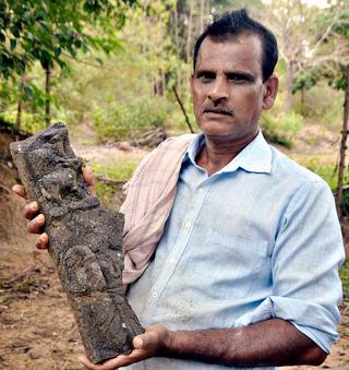 A resident displaying a broken idol that was found on the premises of the temple.