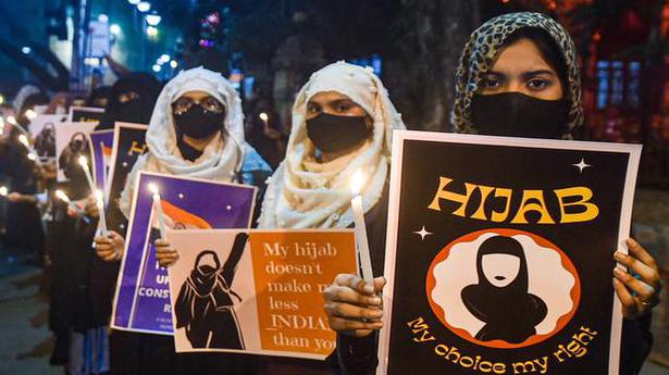 Women holding banners protest the hijab ban