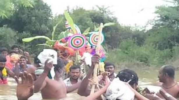 Villagers wade through channel to carry dead man to cremation ground